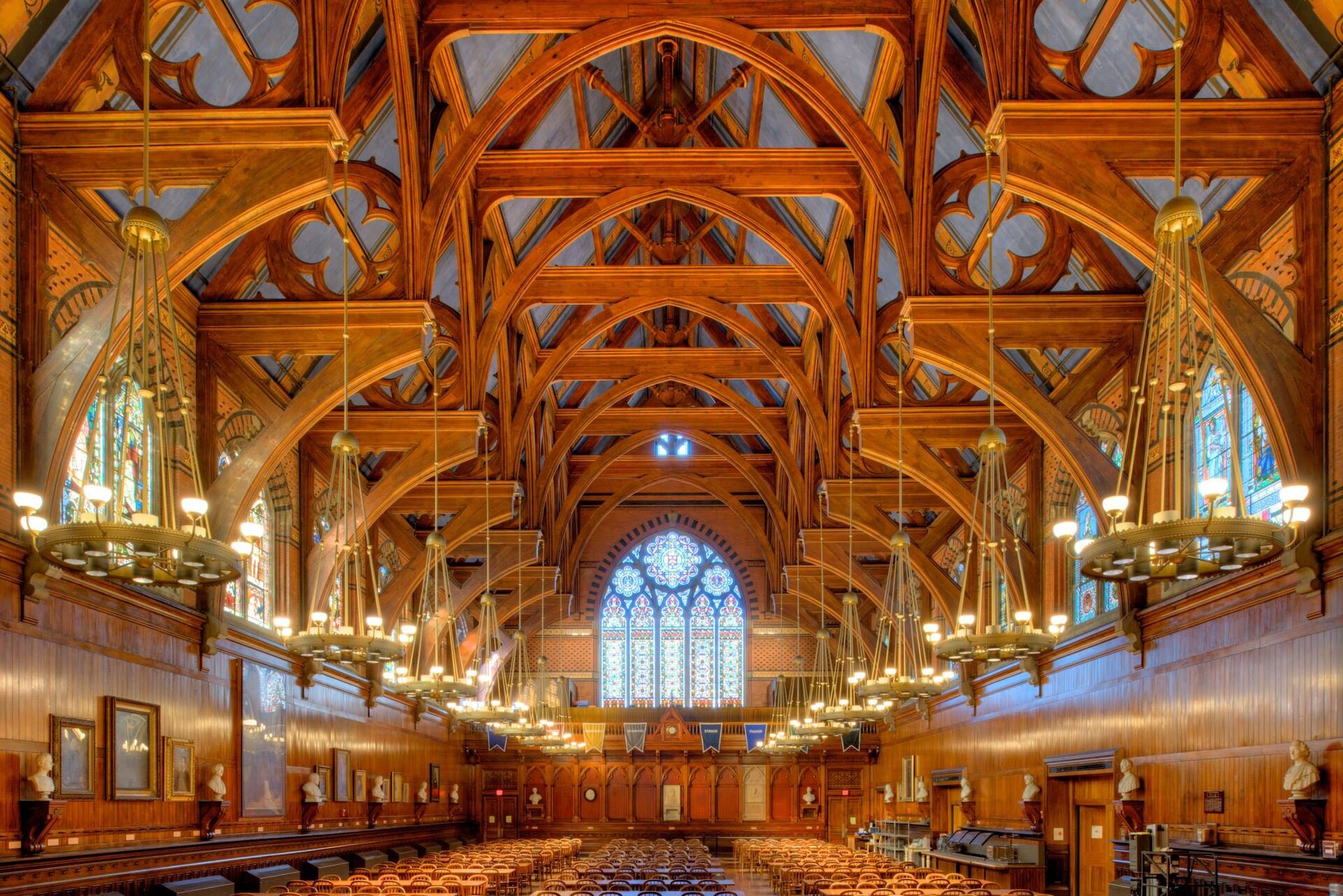 Long wooden tables under the carved timber ceiling and chandeliers of Harvard's Annenberg Hall