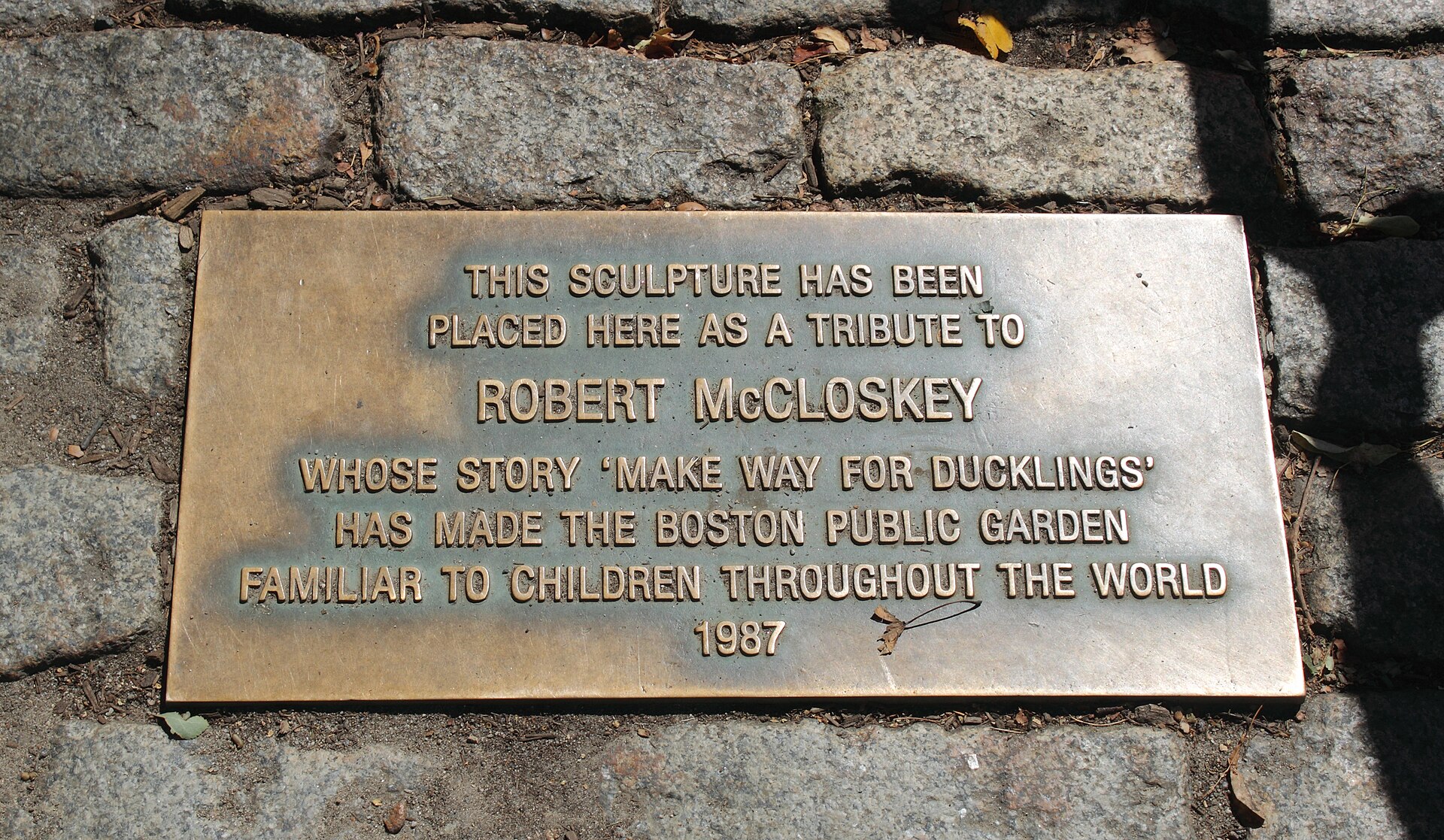 Bronze plaque set in cobblestones: a tribute to Robert McCloskey, whose story Make Way for Ducklings made the Public Garden famous, 1987