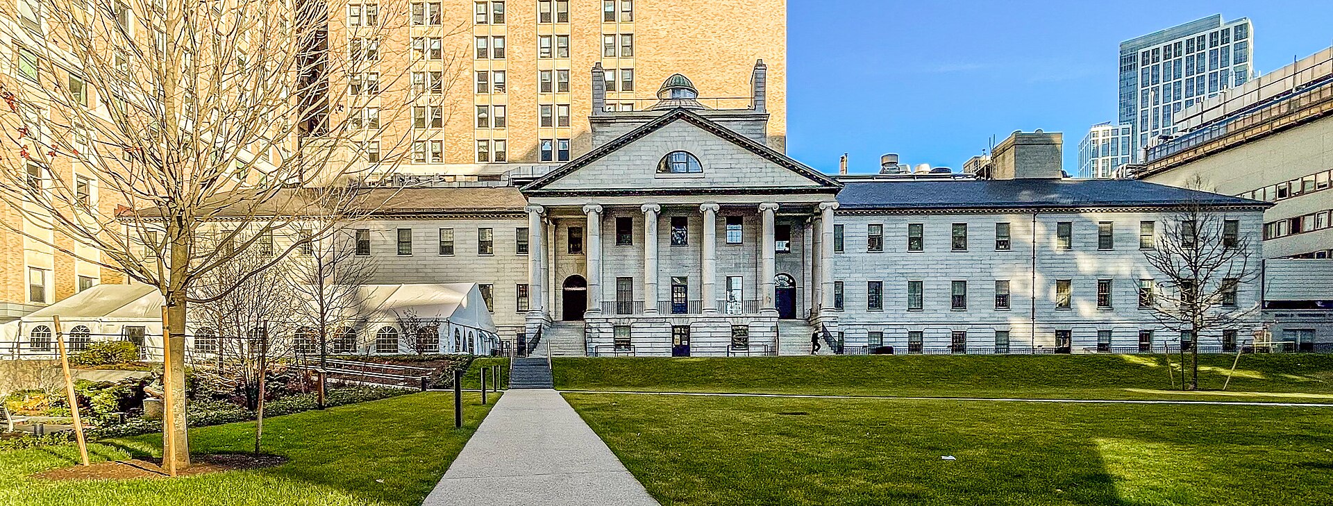 The white granite Bulfinch Building with its columned portico behind a lawn at Massachusetts General Hospital