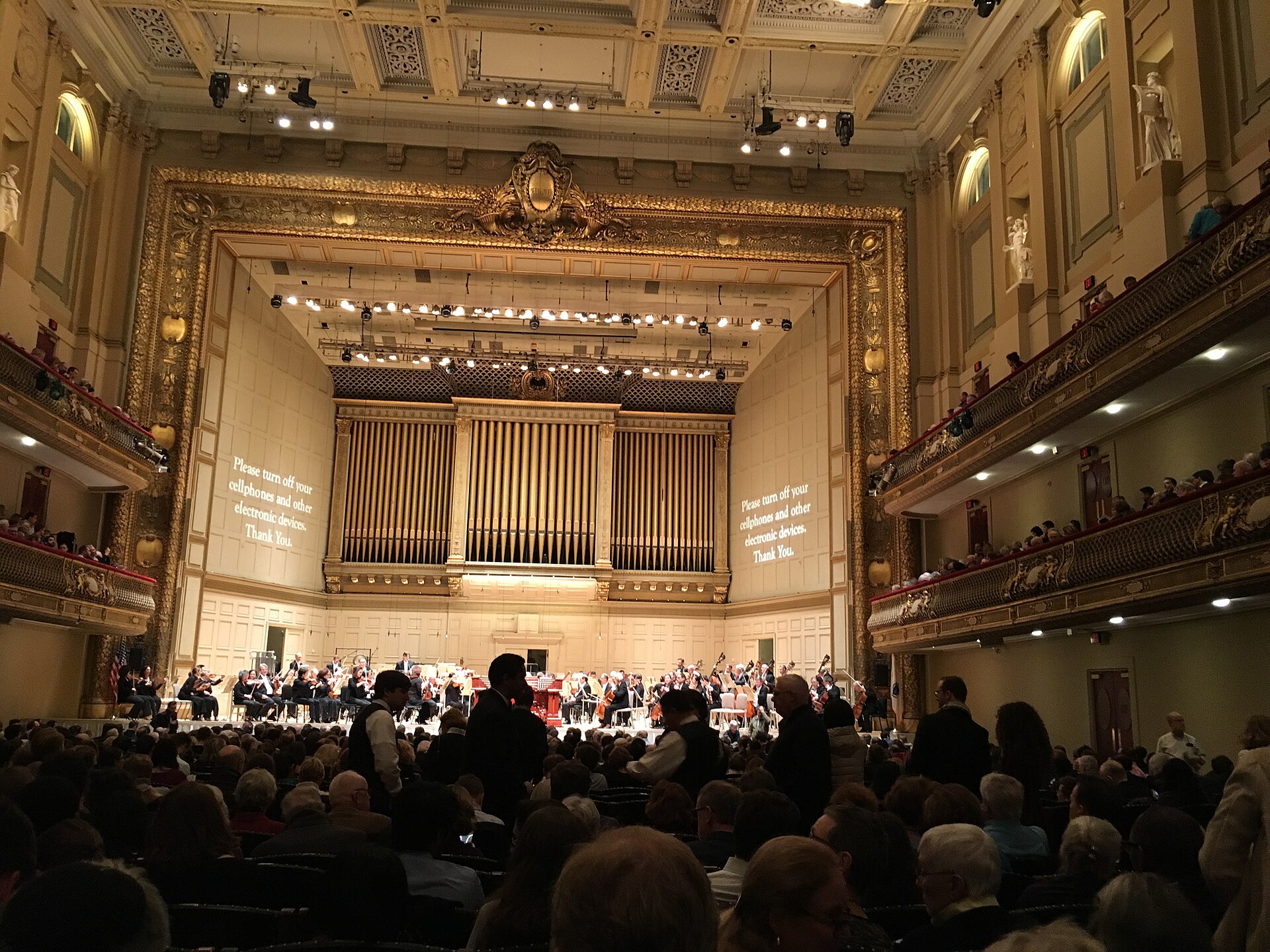 A full audience facing the orchestra and organ pipes inside Boston's Symphony Hall